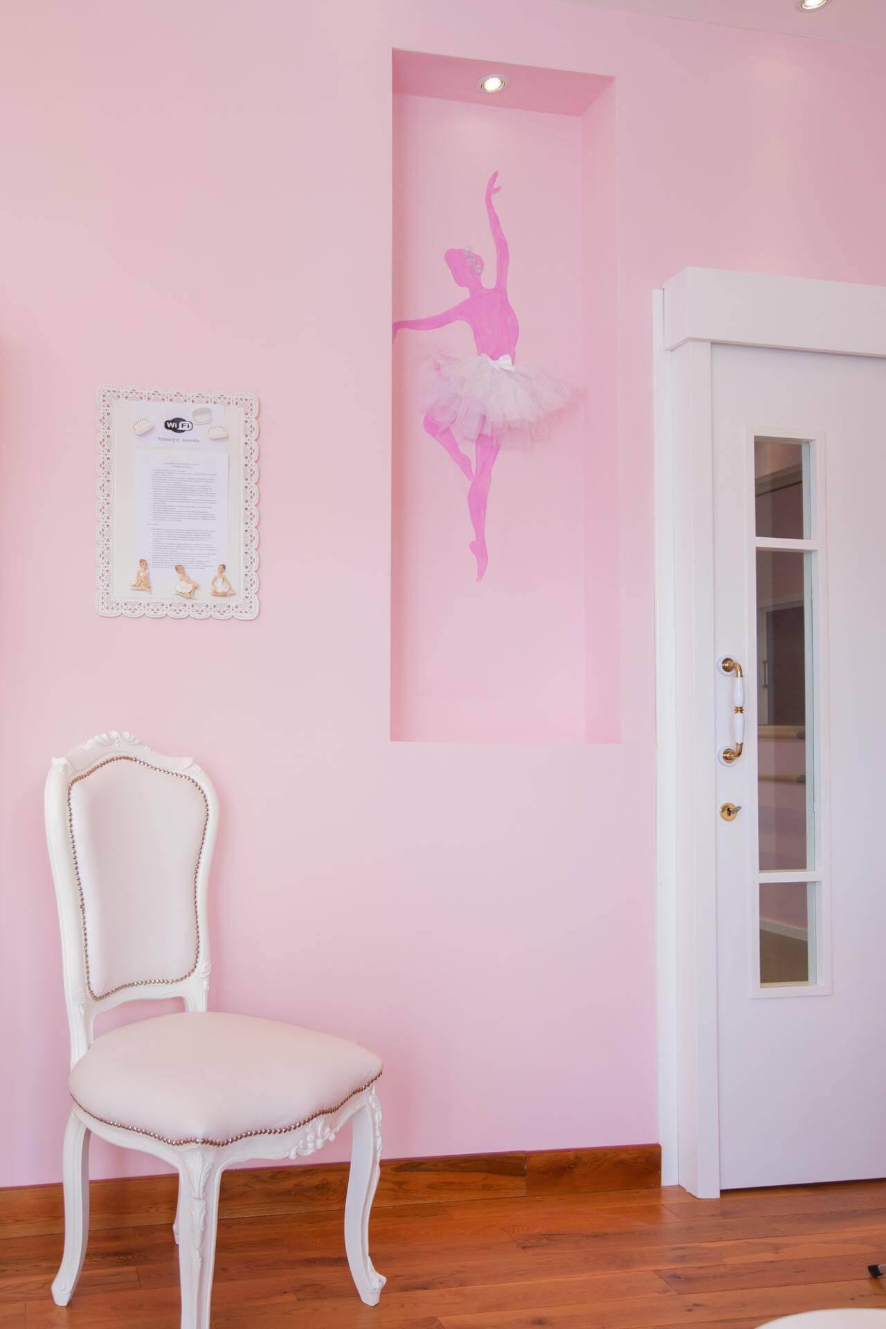 A ballerina painted on the wall beside a white chair