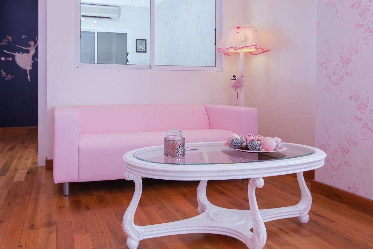 The waiting area with a pink sofa, a lamp and a ballerina mural