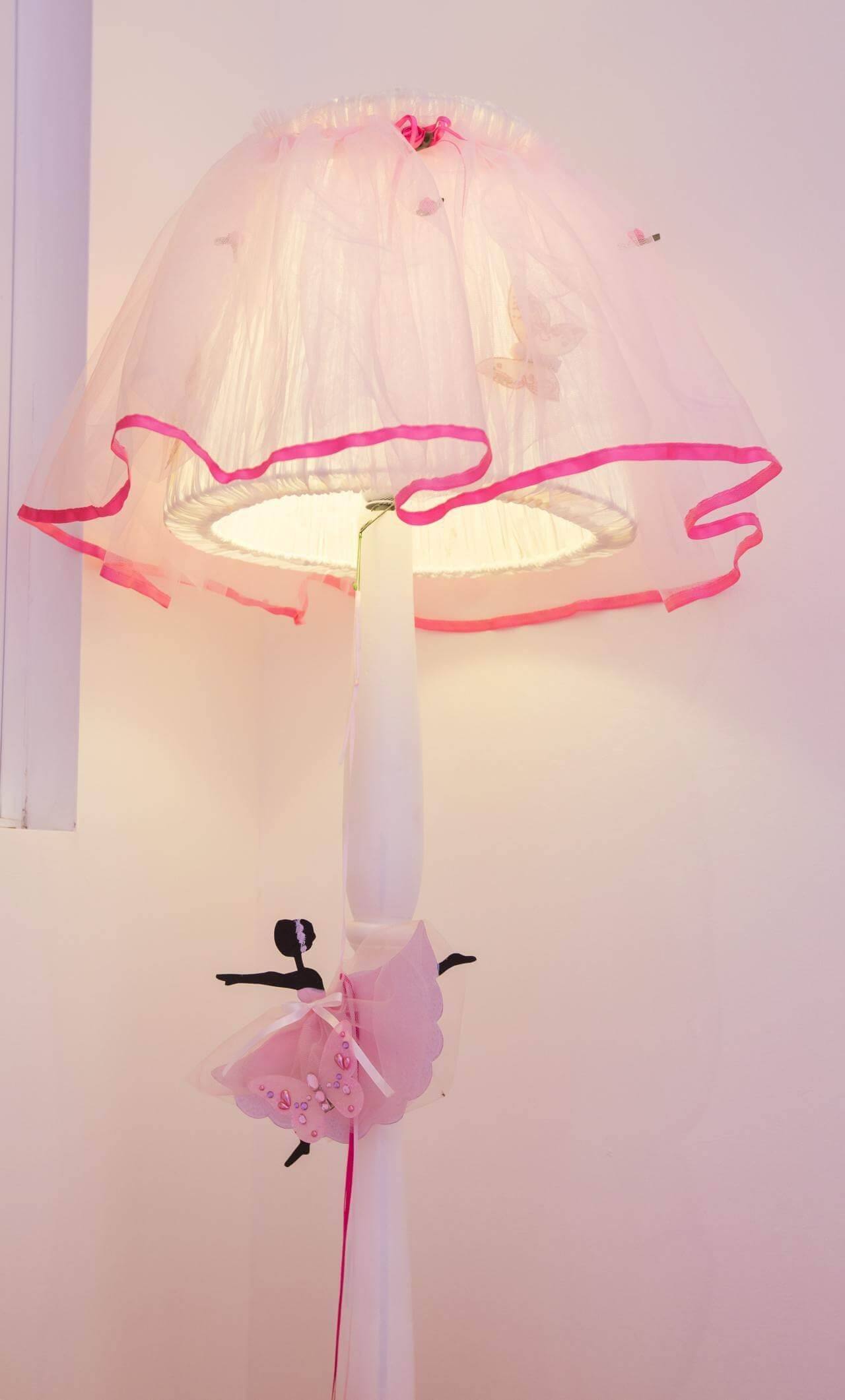 A lamp with a pink shade and a ballerina